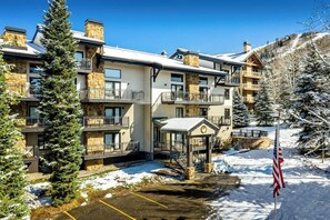 A multi-story hotel with balconies, a covered entrance, and a snow-covered landscape. - Luxury, Top-Floor, Ski-In/Ski-Out Condo w/ Fireplace, Balcony & Shared Hot Tub (Steamboat Springs)