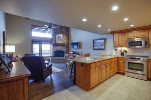 A spacious kitchen with wooden cabinets, a large island, a built-in oven, and a stone fireplace. - Luxury, Top-Floor, Ski-In/Ski-Out Condo w/ Fireplace, Balcony & Shared Hot Tub (Steamboat Springs)