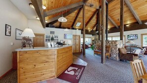 A reception desk with a wooden finish, a stone wall, and a television in the background. - Ski Inn 231 Lofted family condo with ski-in/ski-out access, trails outside, & shared hot tub (Steamboat Springs)