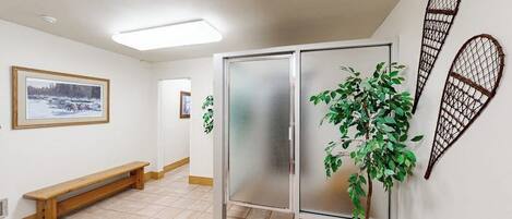 A hallway with a bench, a frosted glass partition, and a potted plant.