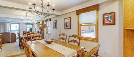 A dining area with a wooden table, chairs, a chandelier, and framed pictures on the walls.
