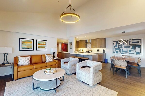 Uma sala de estar moderna com um sofá, poltronas, uma mesa de centro e um espaço de jantar com mesa e cadeiras.
