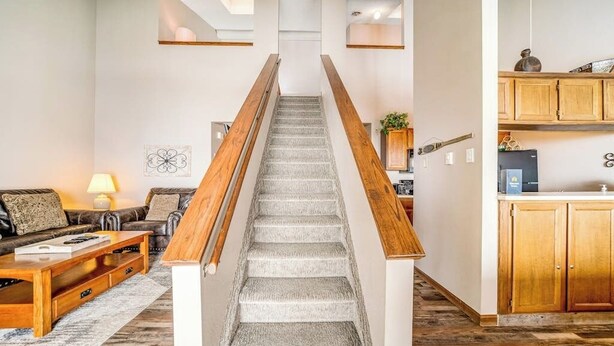 Eine Treppe mit Holzwangen führt zu einer Küchenzeile mit Holzschränken und einem Kühlschrank.