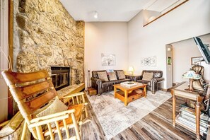 Ein gemütliches Wohnzimmer mit einer Steinwand, Ledersofa, Holzstühlen, einem Kamin und einem Bücherregal.