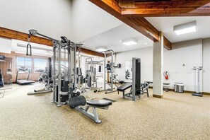 Ein Fitnessraum mit unterschiedlichen Trainingsgeräten, Laufband und Feuerlöscher.