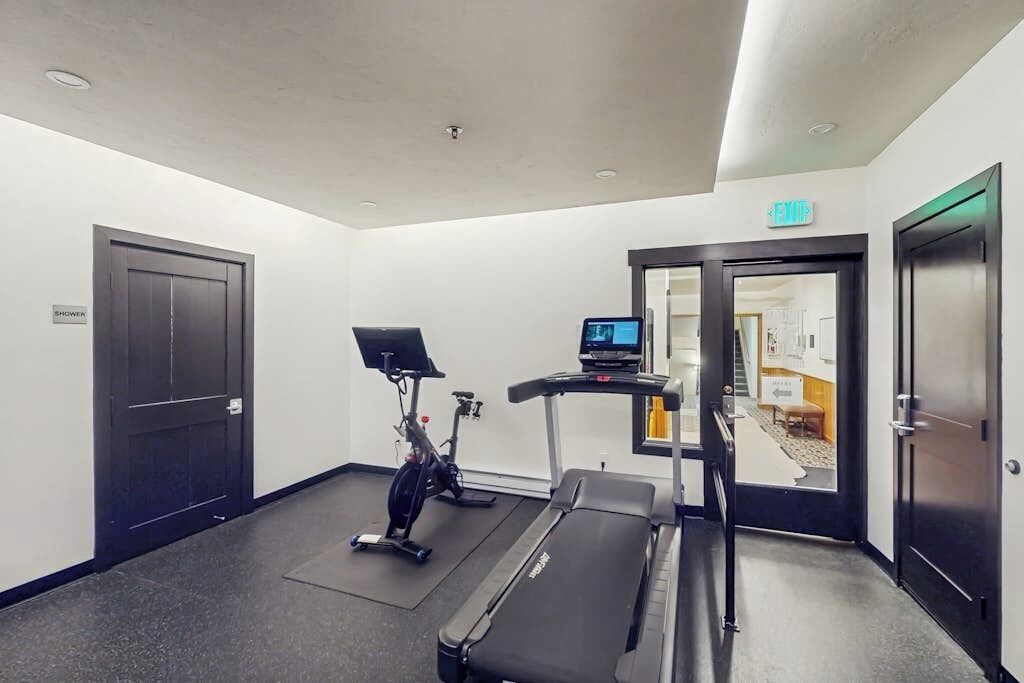 Une chambre d’hôtel équipée d’un tapis de course, d’un vélo d’exercice et d’un petit bureau avec un ordinateur.
