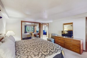 Un dormitorio con cama, cómoda, televisor y espejo.