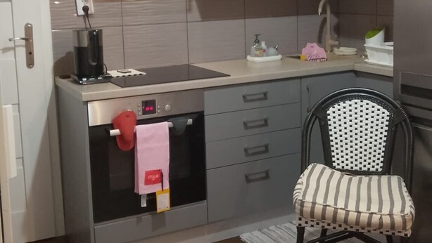 A compact kitchen with a microwave, oven, and a small dining area with a chair and a round table. - Studio Sleeps 1 in Sundbyberg (Sundbyberg)