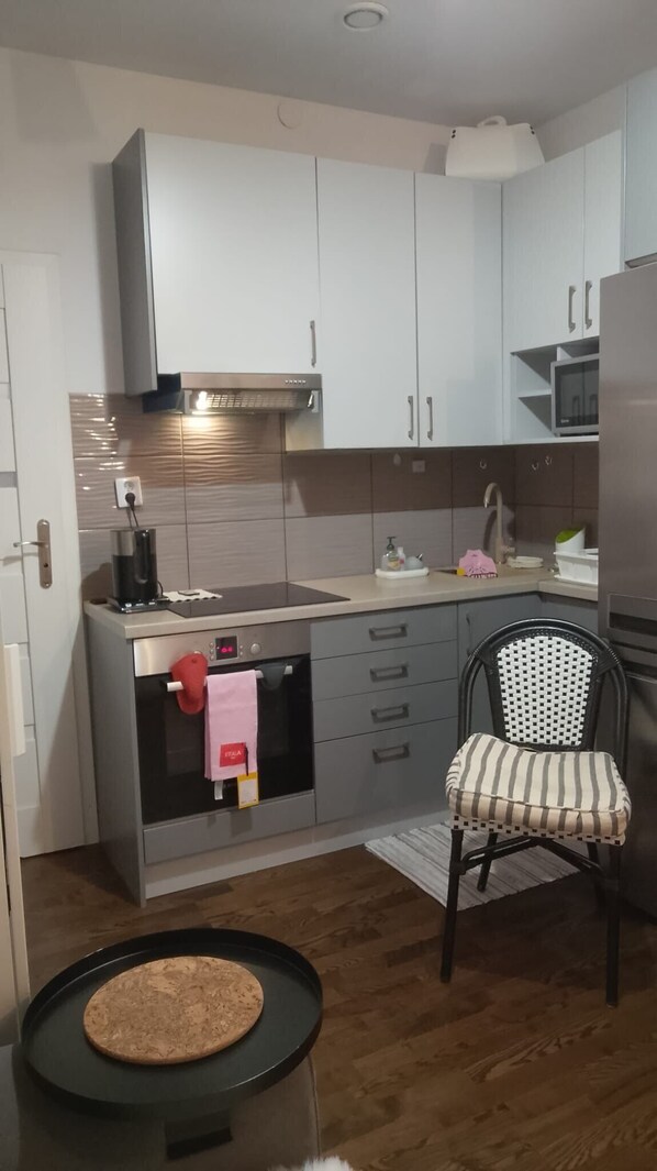 A compact kitchen with a microwave, oven, and a small dining area with a chair and a round table.