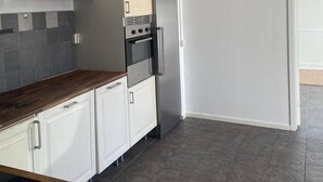 A kitchen with a built-in oven, a refrigerator, white cabinets, a wooden countertop, and a hanging light fixture. - Studio Sleeps 1 in Sundbyberg (Sundbyberg)