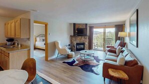A modern hotel room with a kitchen, a fireplace, a sofa, and a dining area. - Ski Inn 211 - 2BR, 2BA ski-in/out condo with mountain views, fireplace, hot tub (Steamboat Springs)