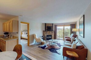 A modern hotel room with a kitchen, a fireplace, a sofa, and a dining area. - Mountain-view condo with private balcony, grill, fireplace, on-site hot tub, gym (Steamboat Springs)