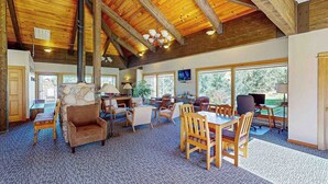 A spacious room with a high wooden ceiling, a fireplace, a dining area, and large windows offering a view of the outdoors. - Ski Inn 211 - 2BR, 2BA ski-in/out condo with mountain views, fireplace, hot tub (Steamboat Springs)