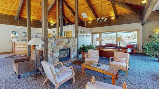A spacious living area with a stone fireplace, wooden ceiling beams, and comfortable seating. - Ski Inn 211 - 2BR, 2BA ski-in/out condo with mountain views, fireplace, hot tub (Steamboat Springs)