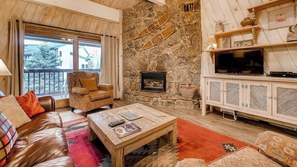 Ein gemütliches Wohnzimmer mit Steinwand, Kamin, Fernseher und einer bequemen Sitzecke.