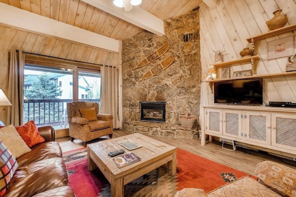 Ein gemütliches Wohnzimmer mit Steinwand, Kamin, Fernseher und einer bequemen Sitzecke.