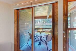 Eine Glastür öffnet sich zu einer Terrasse mit einem runden Tisch und vier Stühlen.