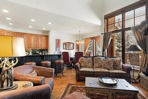 Ein gemütliches Wohnzimmer mit Ledermöbeln, einem Couchtisch und einem Essbereich mit Holzschränken und einer Bar.