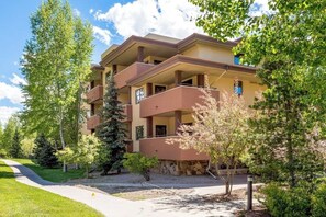 A multi-story building with balconies, surrounded by trees and a pathway. - Spacious condo with pool, hot tub, gym & easy walk to lifts (Steamboat Springs)