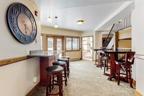 Eine Bar mit Hockern, einer großen Wanduhr und einer Treppe.