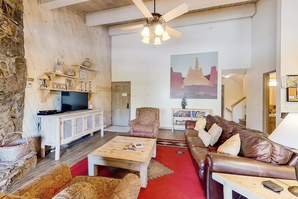 Una sala de estar con televisor, sofá, sillón, mesa de centro y un cuadro en la pared.