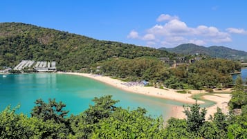 A coastal resort with a sandy beach, a marina, and lush greenery.