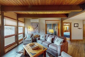 A cozy living room with a wooden ceiling, a sofa, a coffee table, and a window with blinds. - Lovely condo with pool, hot tub, washer/dryer - 1 block to Steamboat Ski Lifts (Steamboat Springs)
