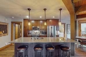 A kitchen with a central island, stainless steel appliances, and hanging pendant lights. - Lovely condo with pool, hot tub, washer/dryer - 1 block to Steamboat Ski Lifts (Steamboat Springs)