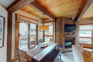 A dining area with a wooden table and chairs, a fireplace, and a television mounted on the wall. - Lovely condo with pool, hot tub, washer/dryer - 1 block to Steamboat Ski Lifts (Steamboat Springs)