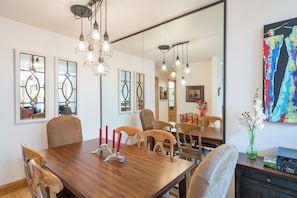 A dining area with a wooden table, chairs, a chandelier, and a large mirror. - Ski-in/out condo with hot tub, grill, balcony & covered parking (Telluride)