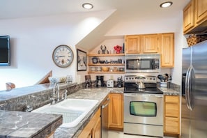 A modern kitchen with a built-in oven, microwave, and stainless steel refrigerator. - Ski-in/out condo with hot tub, grill, balcony & covered parking (Telluride)