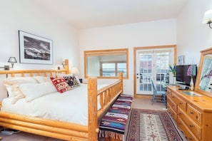 A bedroom with a wooden bed, a television, a dresser, and a large window. - Ski-in/out condo with hot tub, grill, balcony & covered parking (Telluride)
