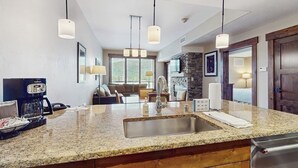 A kitchen with granite countertops, stainless steel appliances, pendant lighting, and a stone backsplash. - Convenient Home Close to Steamboat Ski Resort, Hiking Trails, Restaurants & More (Steamboat Springs)