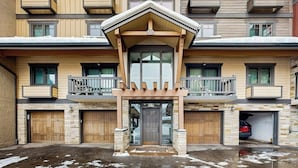Un immeuble à plusieurs étages doté d’une entrée centrale, de balcons et d’un garage.