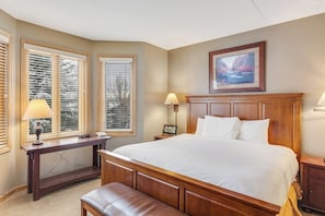 Ein Schlafzimmer mit einem großen Bett, einem hölzernen Kopfteil, einem Schreibtisch und einer Bank.