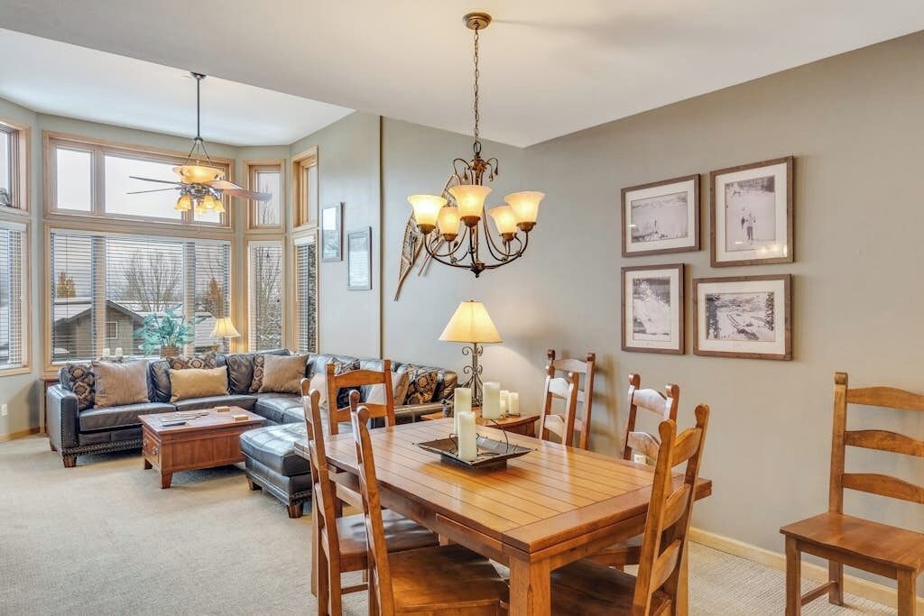 A dining area with a wooden table, chairs, a chandelier, and framed pictures on the wall.