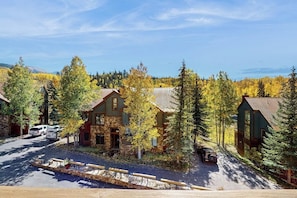 A lodge with a stone facade, surrounded by trees and a clear sky. - Cozy condo with fireplace, W/D, wifi & ski in / out access (Mountain Village)