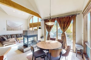 A modern living room with a fireplace, a round dining table, and a sofa. - Cozy condo with fireplace, W/D, wifi & ski in / out access (Mountain Village)