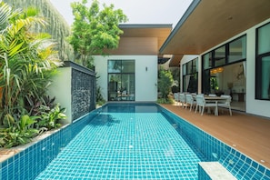 A modern outdoor pool with a wooden deck and seating area, surrounded by lush greenery. - Ruby Luxury Villa, 4 Bed Private Pool Paradise (Rawai)