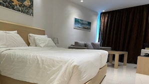 A modern hotel room with a large bed, a small sofa, a desk, and a painting on the wall.