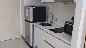 A compact kitchen with a refrigerator, sink, and microwave.