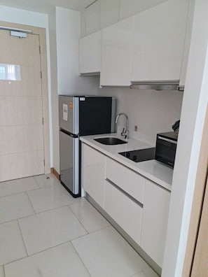Eine kleine Küche mit Kühlschrank, Spüle und Mikrowelle.