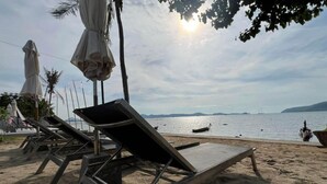 A beach with lounge chairs and umbrellas, a clear sky, and a calm sea.