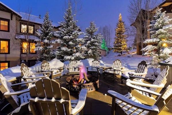 A snow-covered outdoor seating area with Adirondack chairs and a fire pit. - Spacious Corner Home w/ Incredible View, Free WiFi, Private Hot Tub & Large Deck (Steamboat Springs)