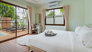 A hotel room with a bed, a chair, a small table, a window with curtains, and a view of the outside. - NEW Tulip 4 Bedroom Pool Villa  Chalong Phuket (Chalong)