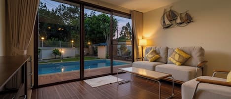 Una sala de estar moderna con un sofá, una mesa de centro y vista a una piscina al aire libre.