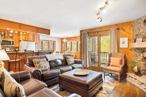 A cozy living room with a leather sofa, ottoman, and a stone fireplace. - Classic ski condo with hot tub, pool, high-speed WiFi & fireplace (Steamboat Springs)
