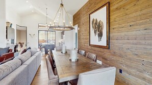 Un comedor con una larga mesa de madera, asientos acolchados y un candelabro.
