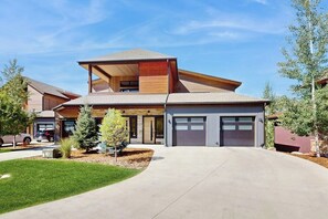 Ein modernes, zweistöckiges Haus mit Garage, überdachter Terrasse und gepflegtem Rasen.