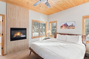 Ein Schlafzimmer mit Kamin, einem Bett, Deckenventilator und einem Gemälde an der Wand.